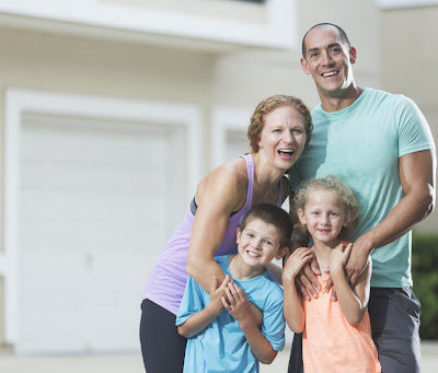 A family with two young children, standing outside in front of garage door for safety