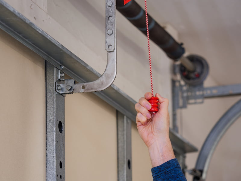 Emergency Release Cord Hand puling on a garage door emergency release cord